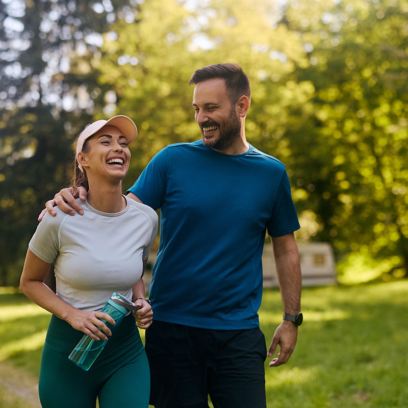 Male and female smiling in workout clothes out for a run